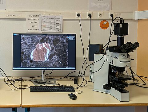Photo d'un microscope équipé d'une caméra à droite et du moniteur de pilotage permettant d'imager les observatiosn.
