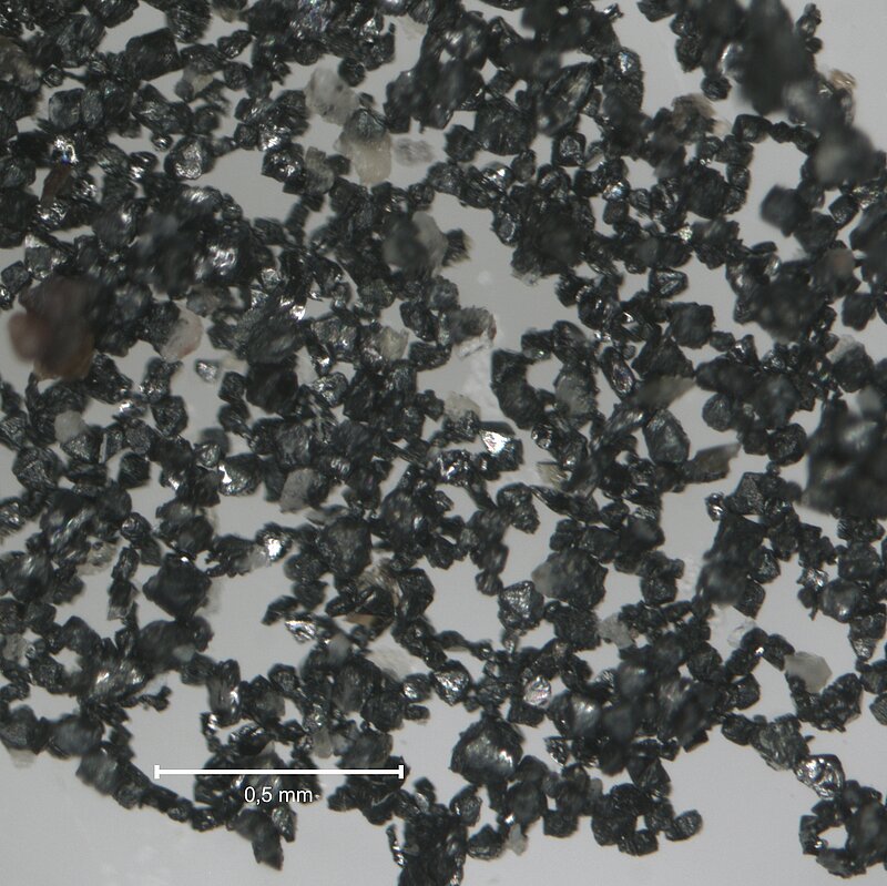 Photo de grains de magnétite séparés à l'aide du Frantz, vus à la loupe binoculaire (grossissement à préciser)